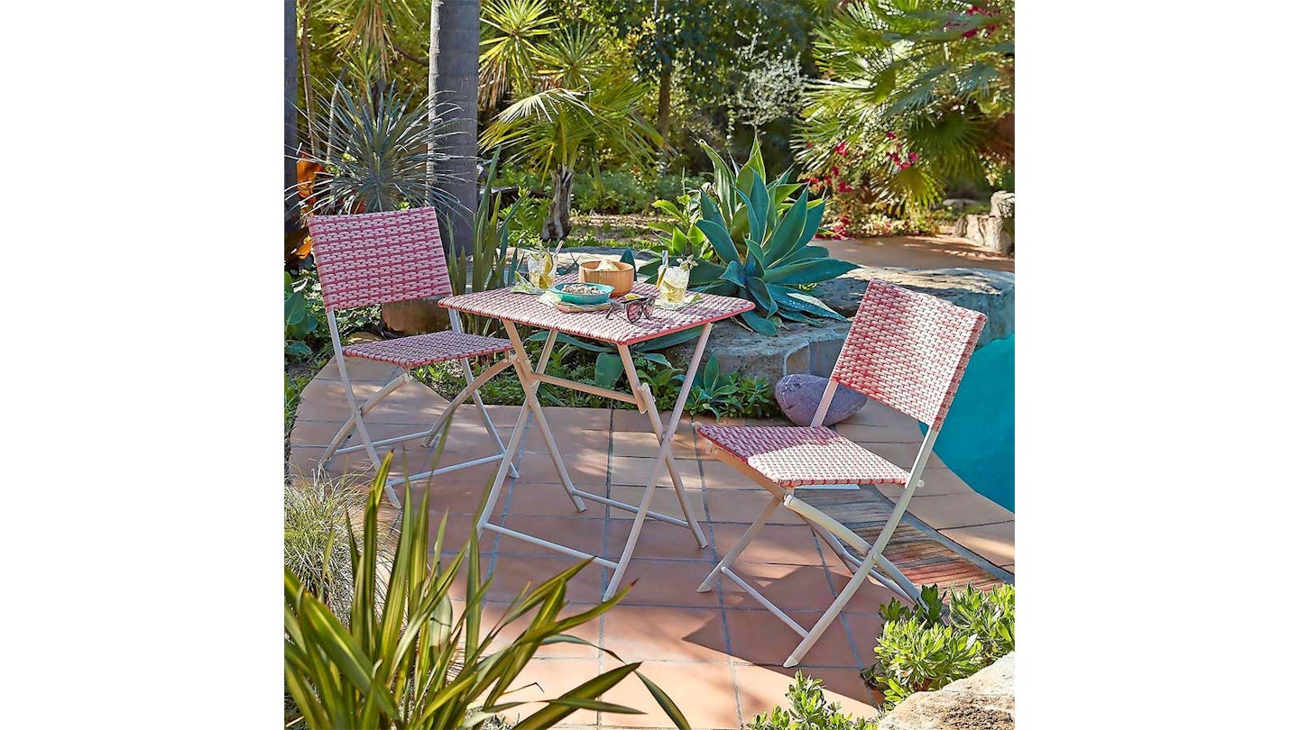 pink bistro set on sunny patio surrounded by lush plants