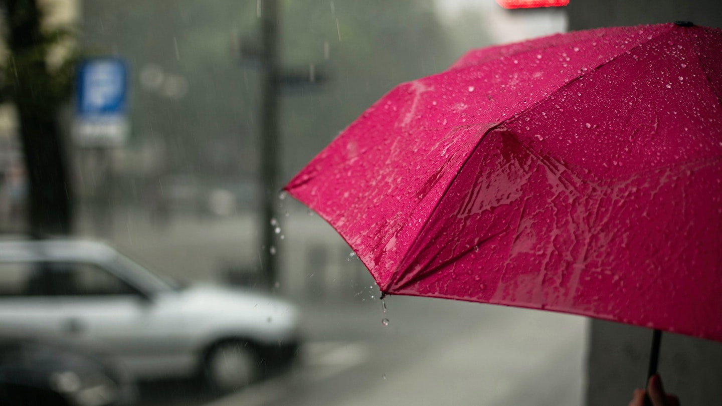 A pink umbrella being used in the rain