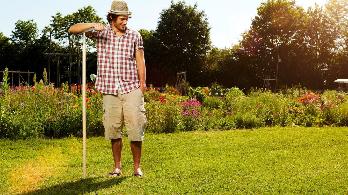 Man standing with rake looking at lawn