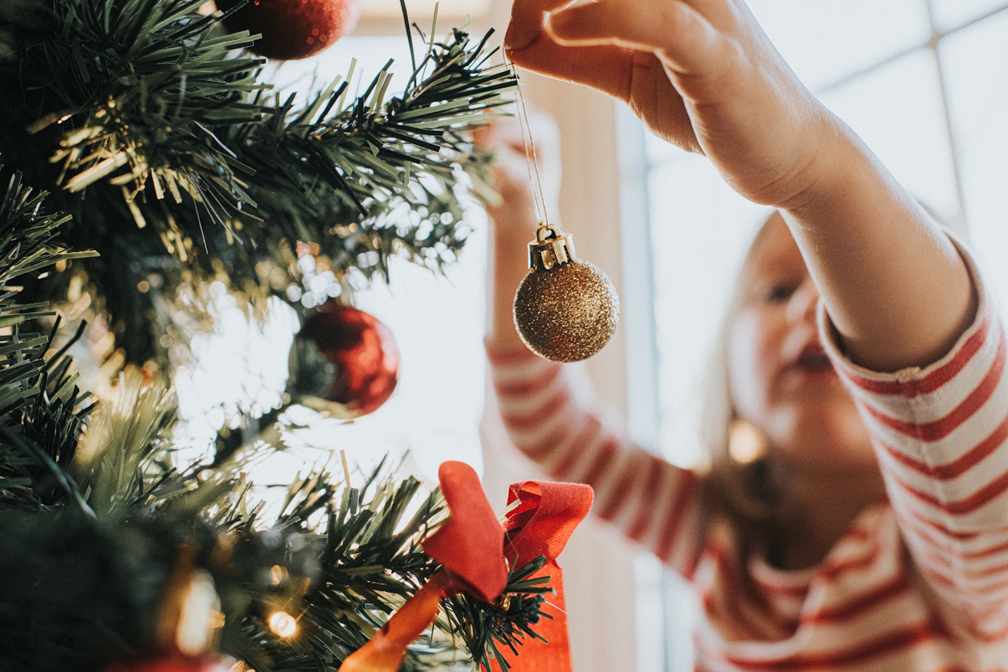Child placing bauble on tree