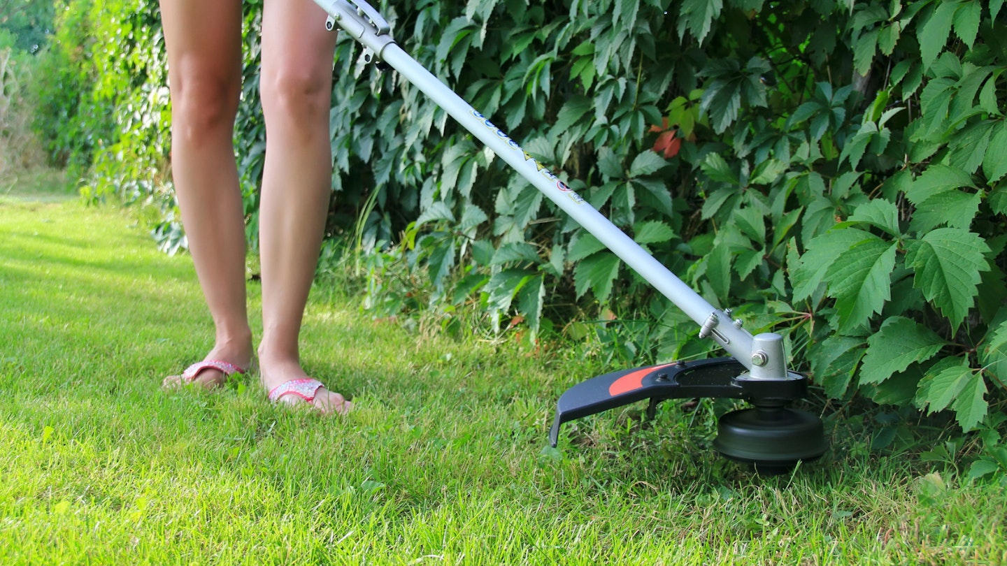 Woman using cordless strimmer