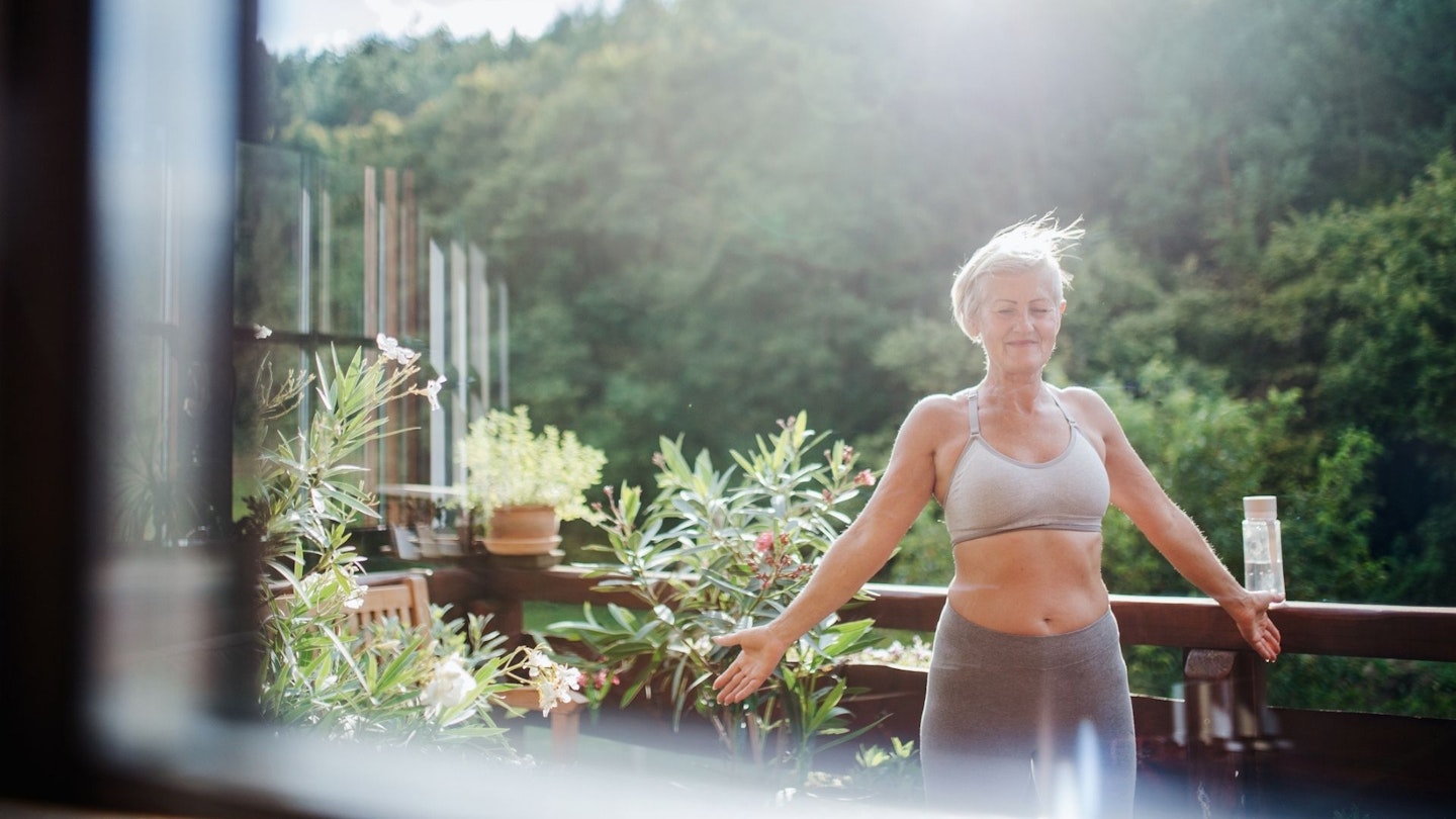 Best sports bras: a senior woman with sports bra on a terrace in summer, doing exercise