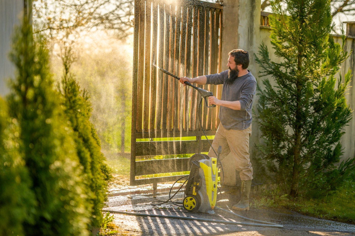 the best pressure washers - modern gardens - man pressure washing a gate