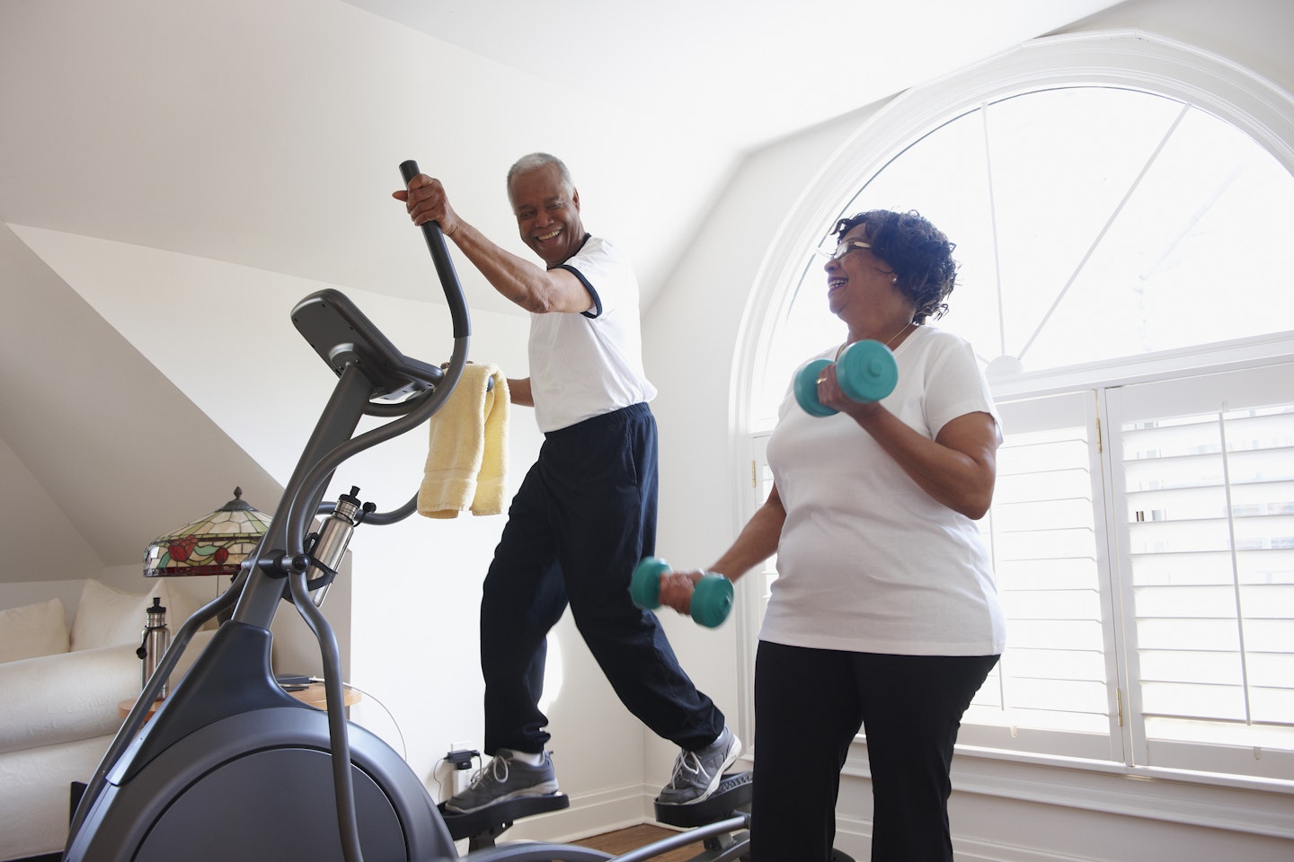 An older couple working out on a home cross trainer and with dumbbells - Yours
