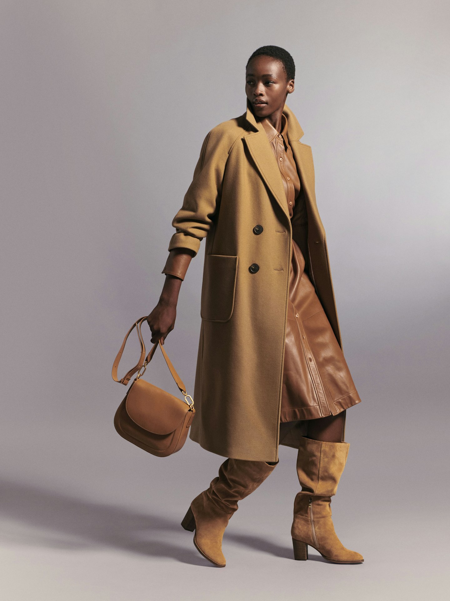 A model wearing a brown coat, boots and bag