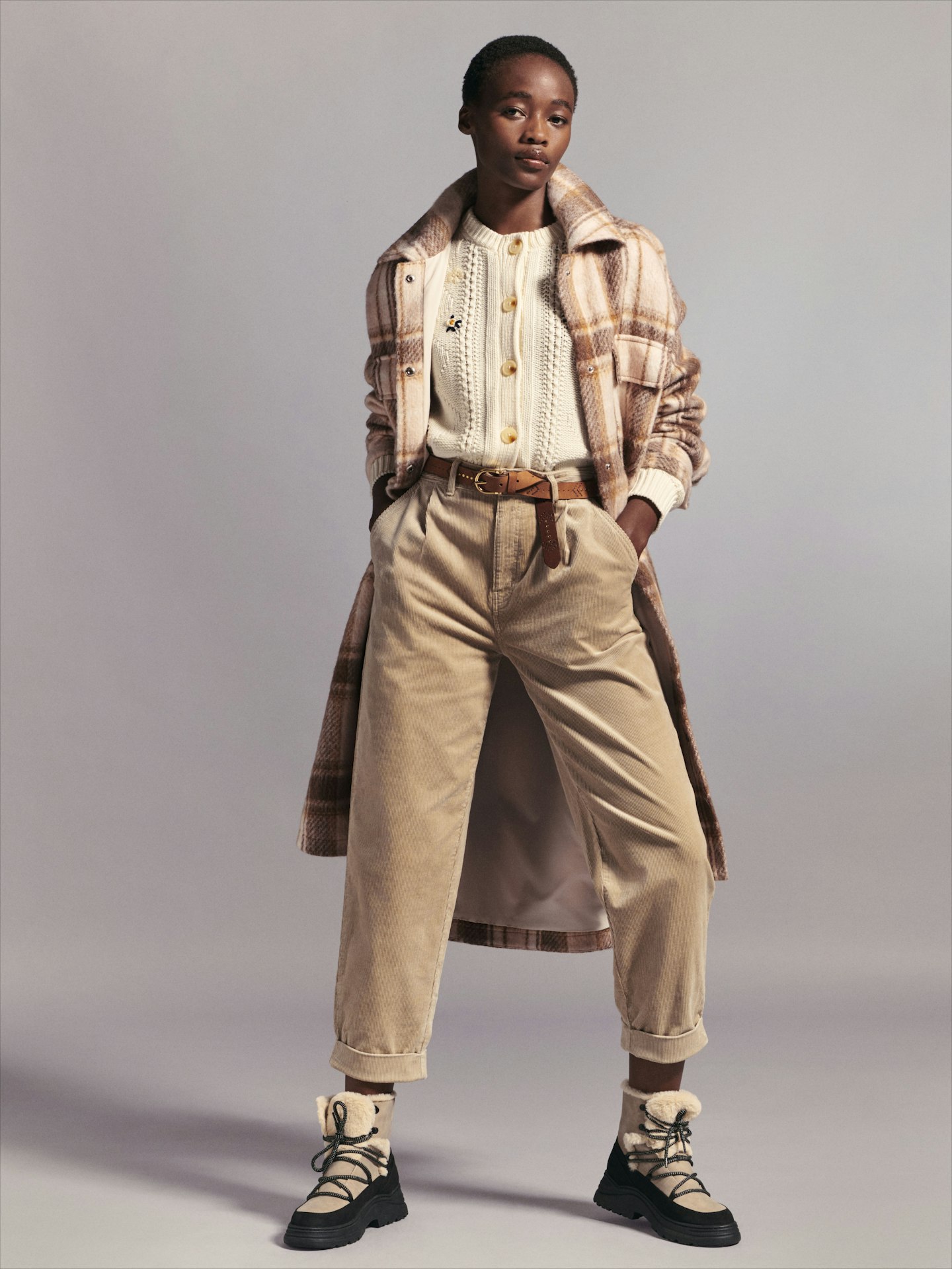 A model wearing a cream cardigan and hiking boots