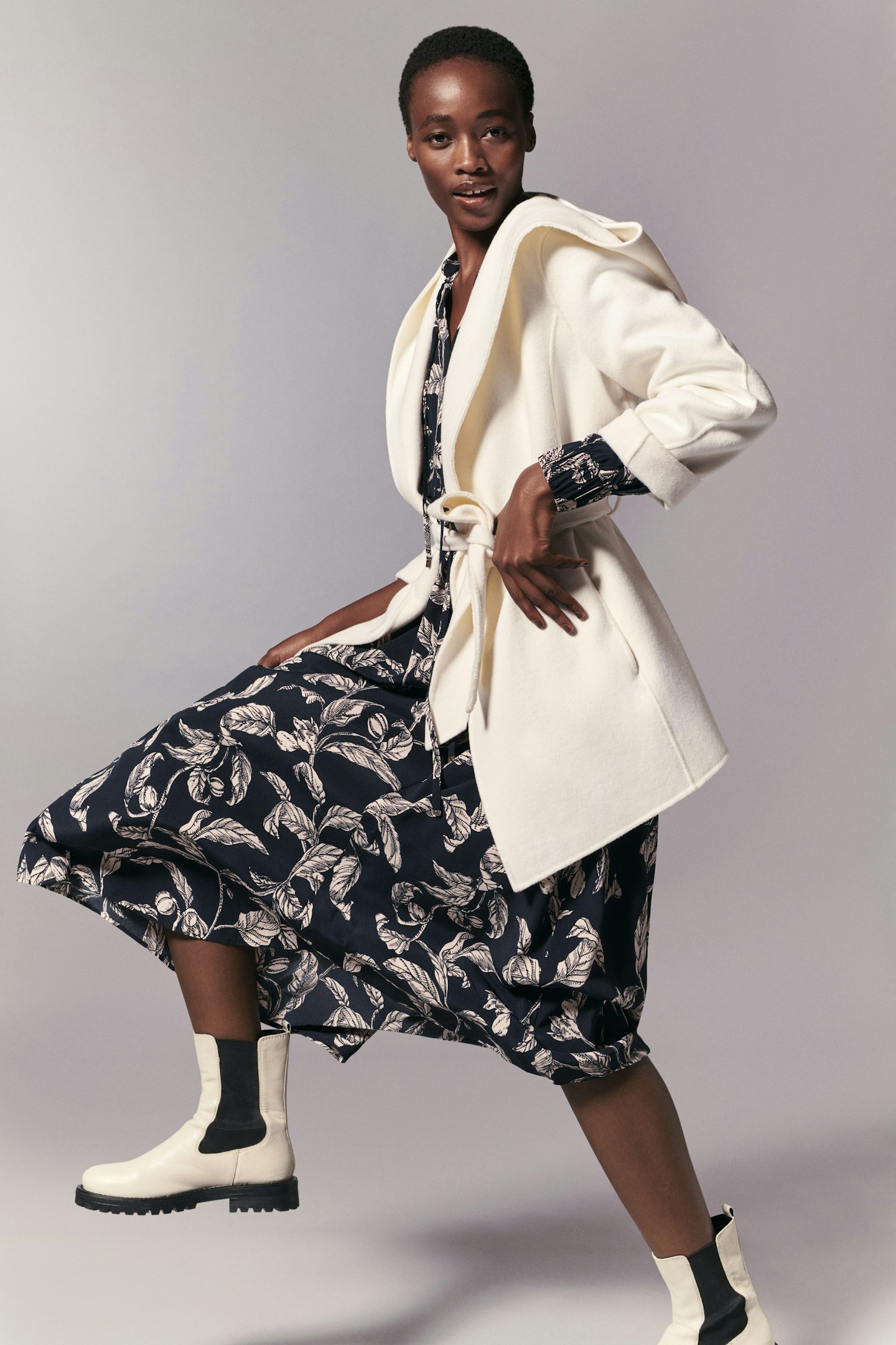 A model wearing a navy floral dress and white boots