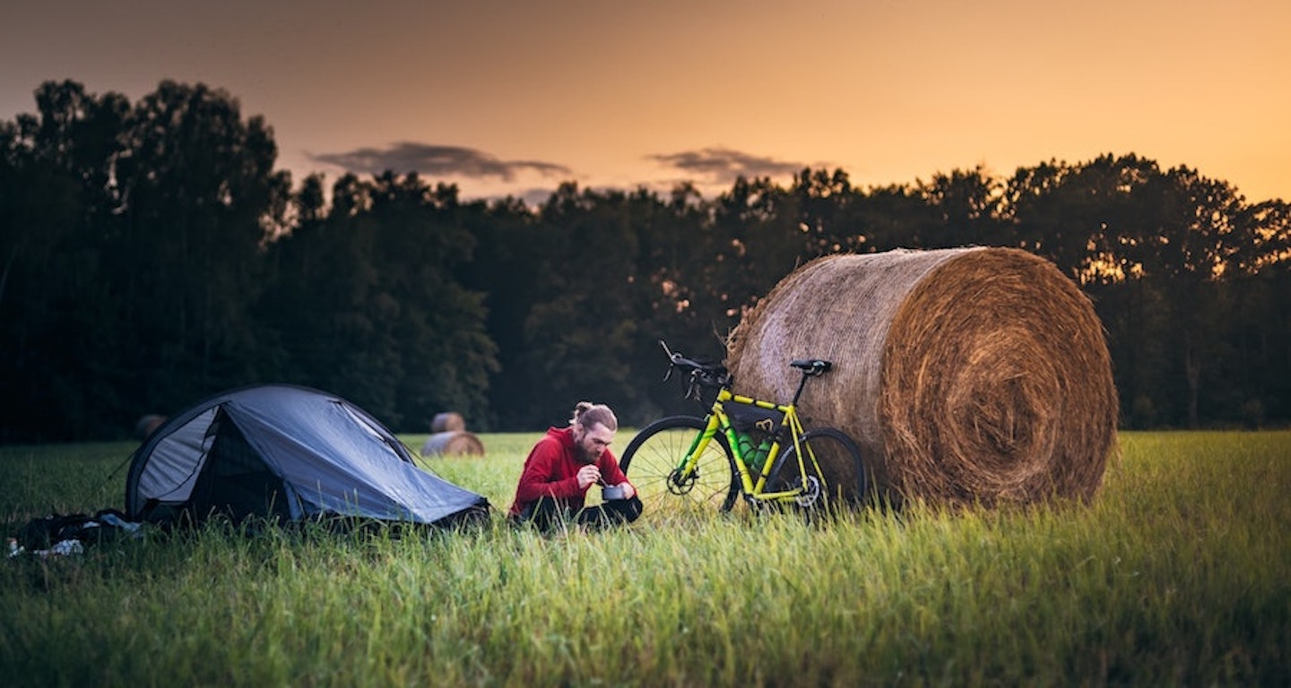 Bike packing man eating next to his tent