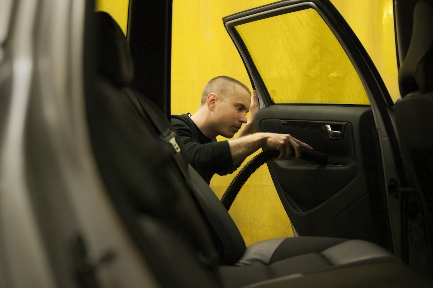A man vacuuming a car door.