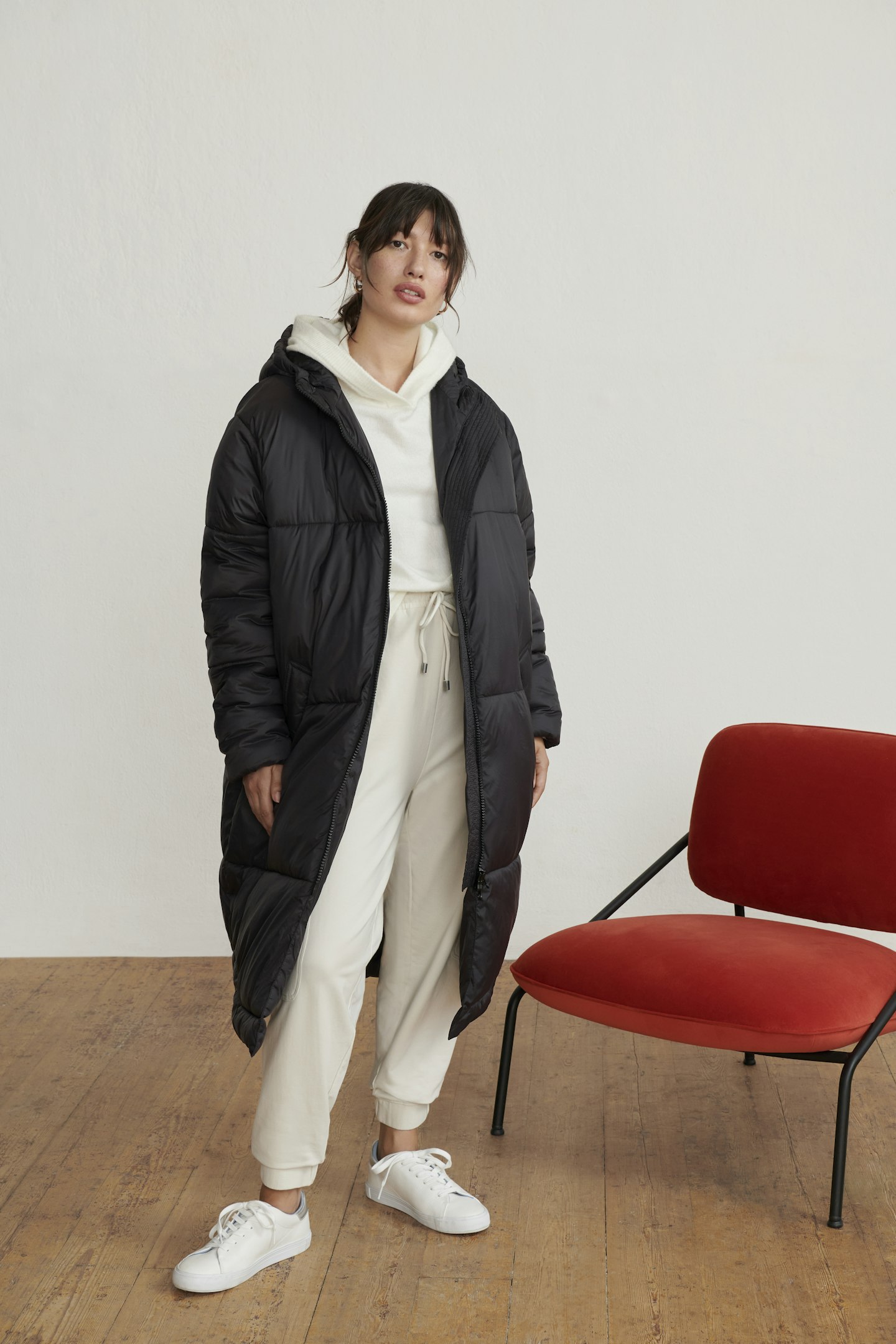 A model wearing a cream loungewear set and black puffer coat 