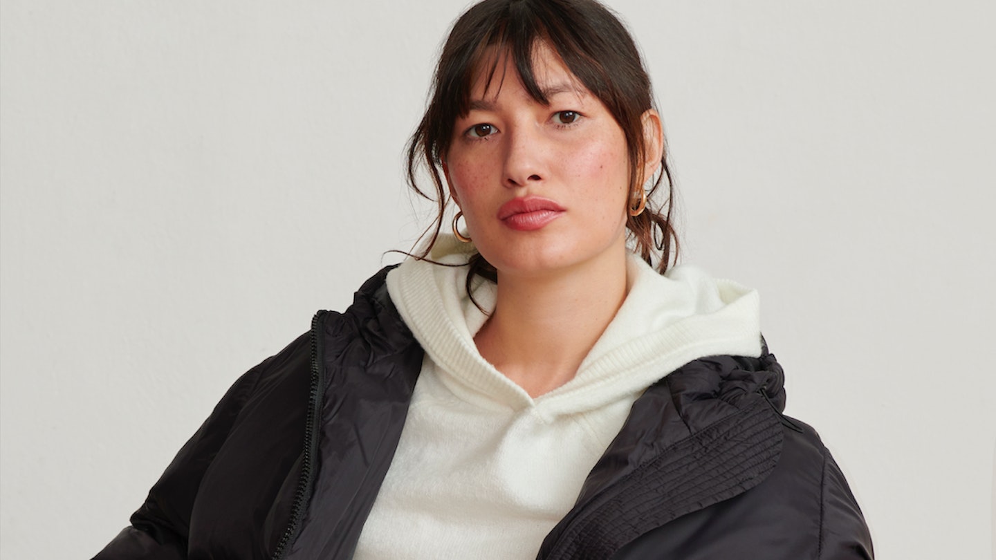 A model wearing a cream hoodie and black puffer coat