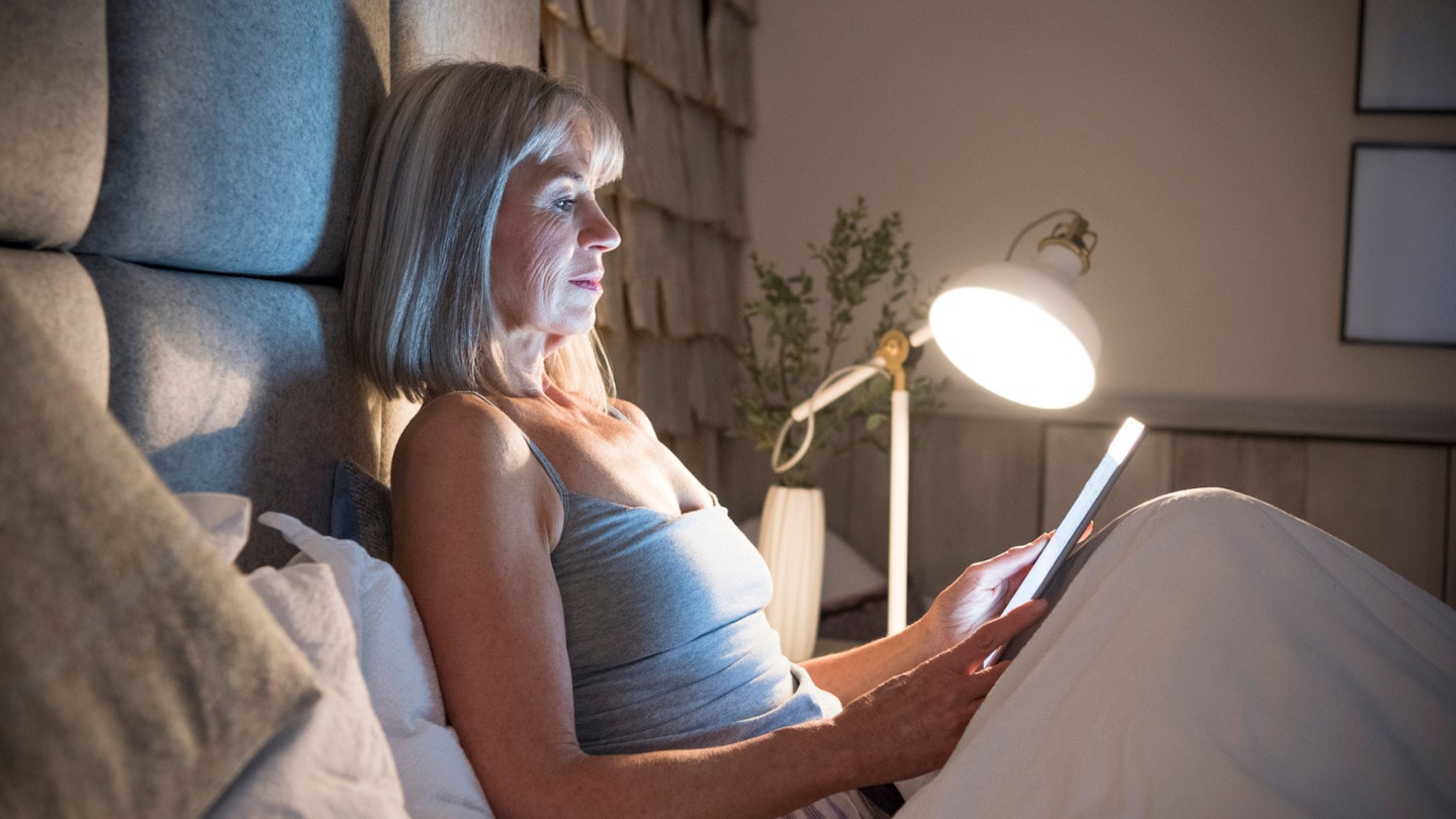 Woman reading in bed with reading light