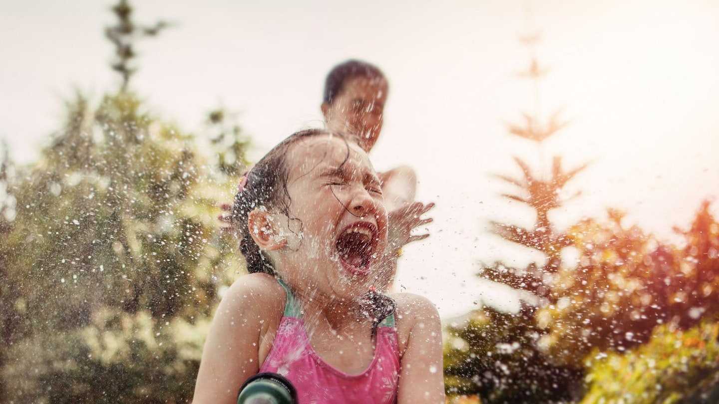 Child playing with hose - the best splash pads for kids