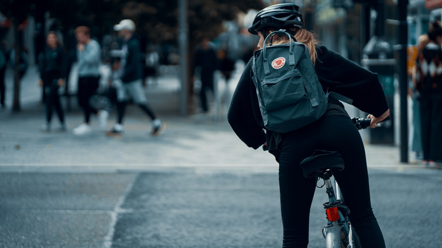 An image of a woman cycling with a backpack on