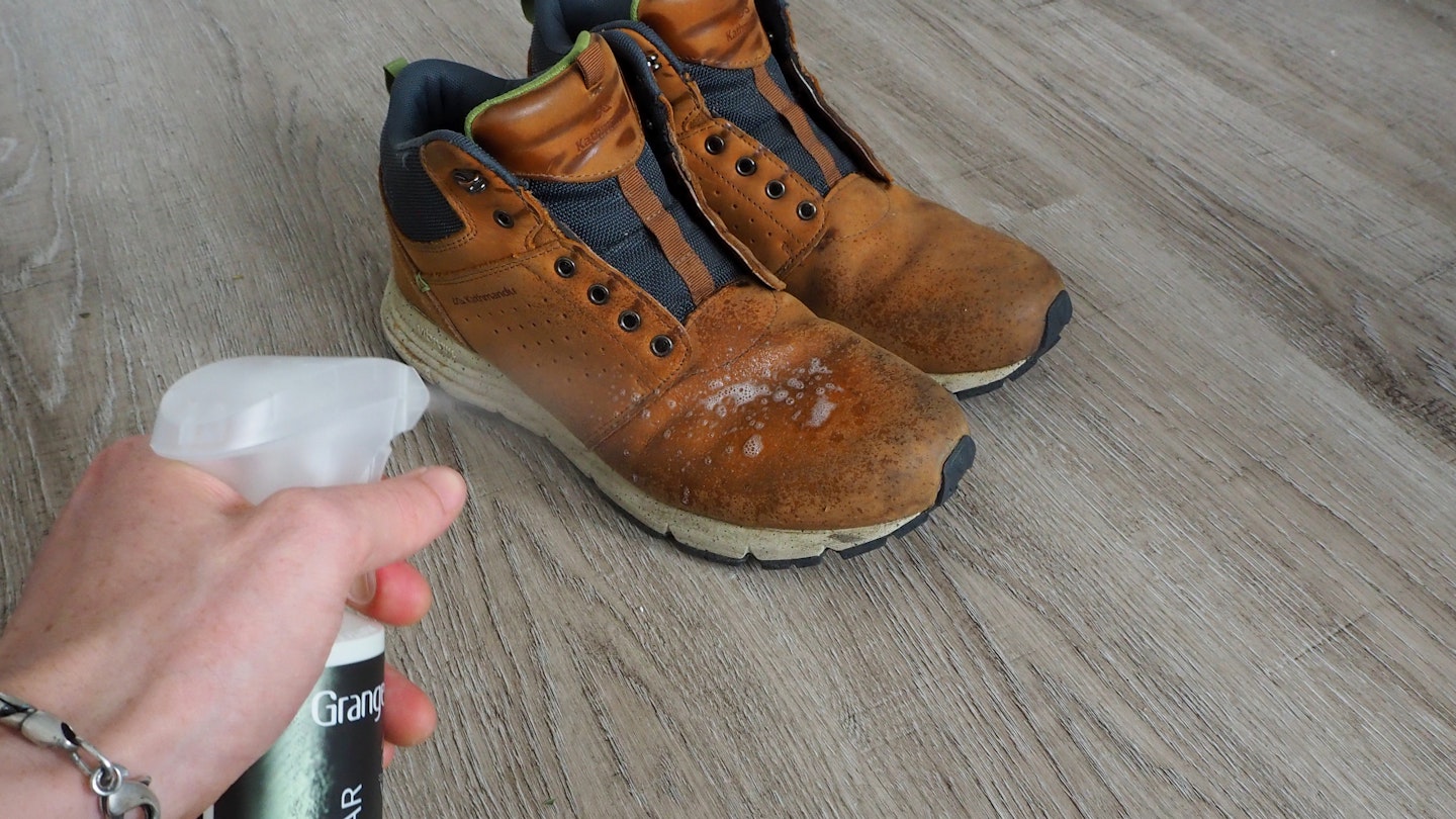 Spraying Grangers Footwear + Gear Cleaner onto dirty shoes