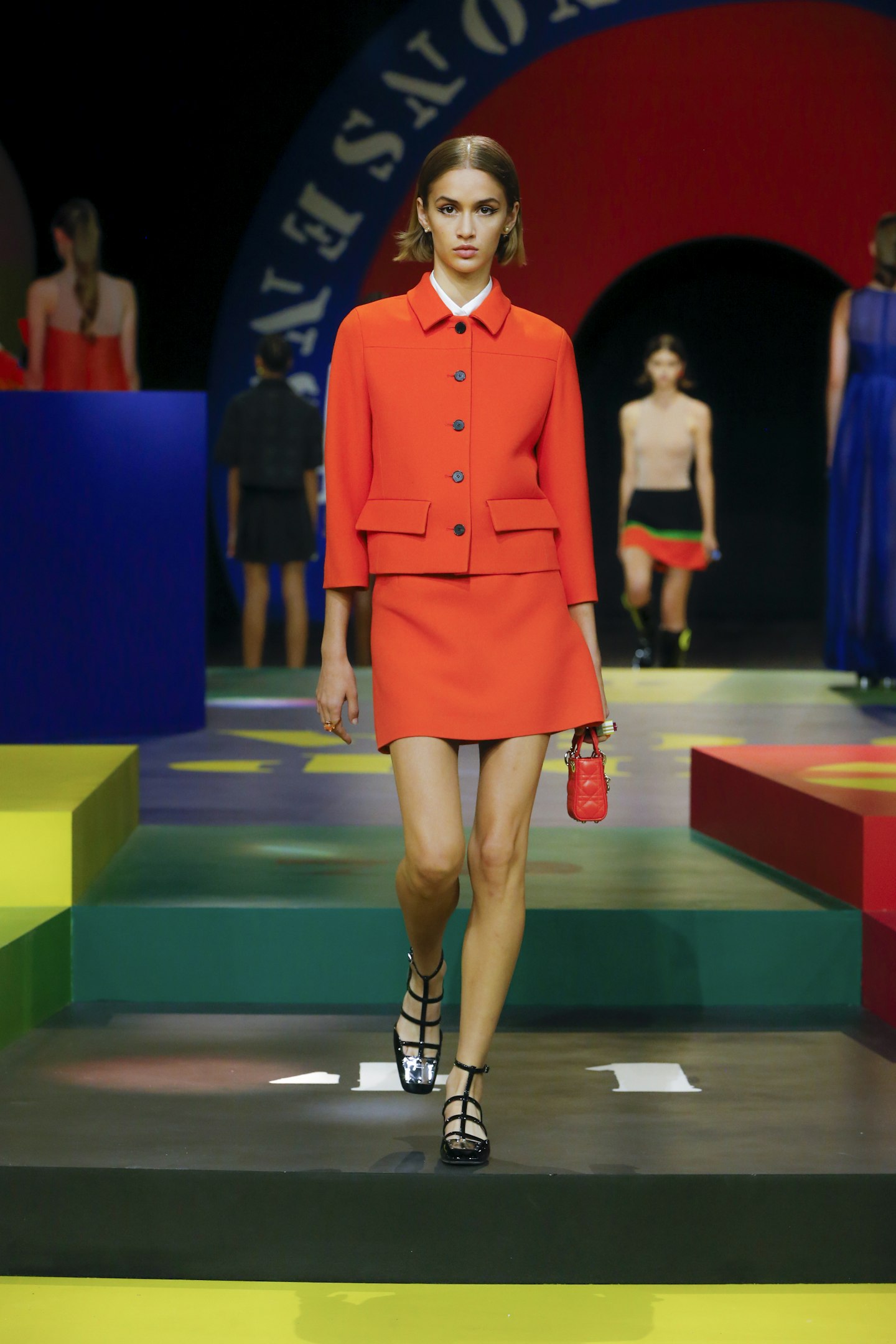 A model wearing an orange skirt suit from Dior