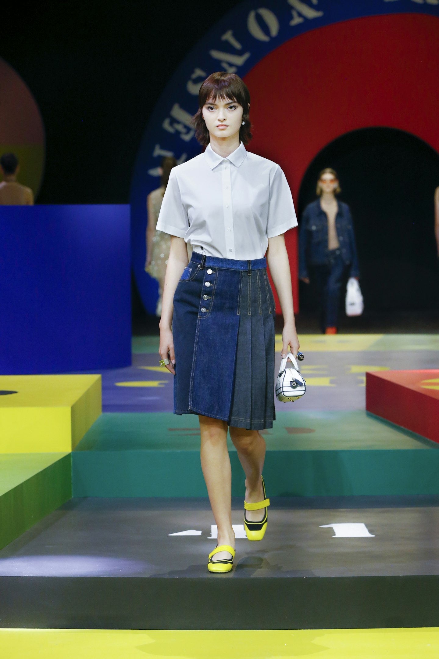 A model wearing a denim pleated skirt at Dior