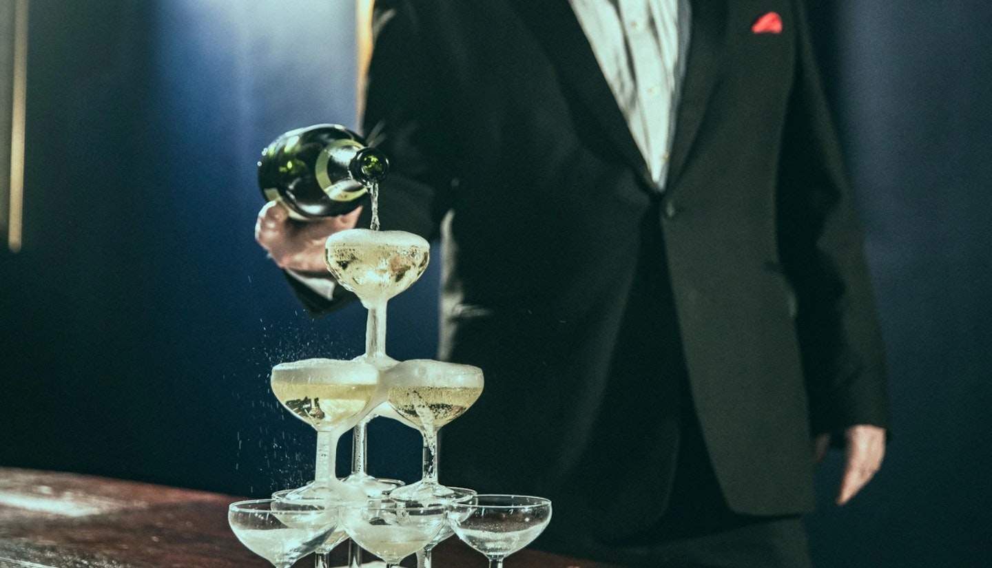 waiter pouring champagne into glass tower