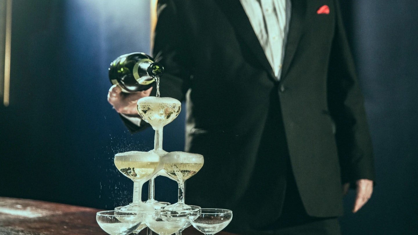 waiter pouring champagne into glass tower