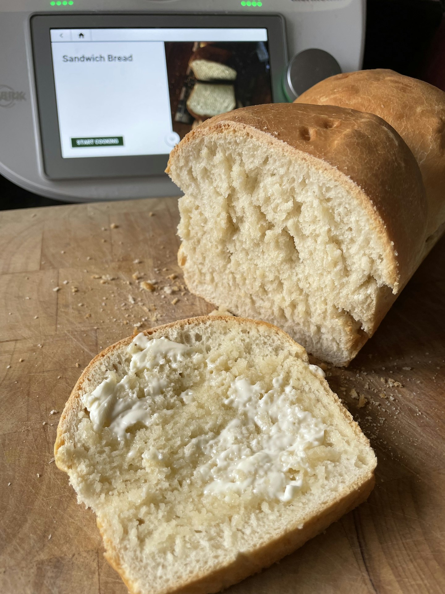 A loaf of homemade white bread, in front of the Thermomix