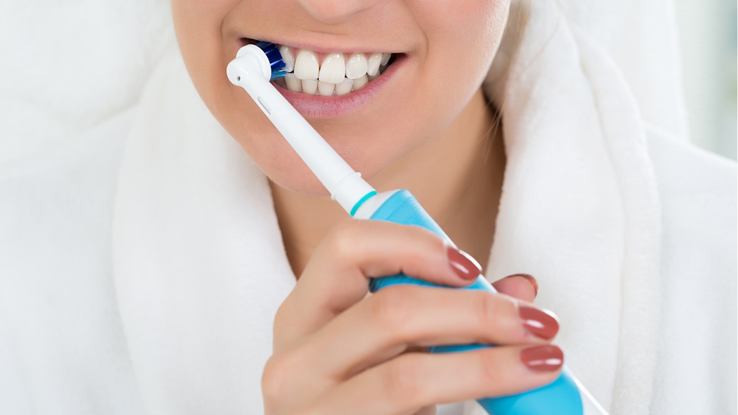 Woman using electric toothbrush