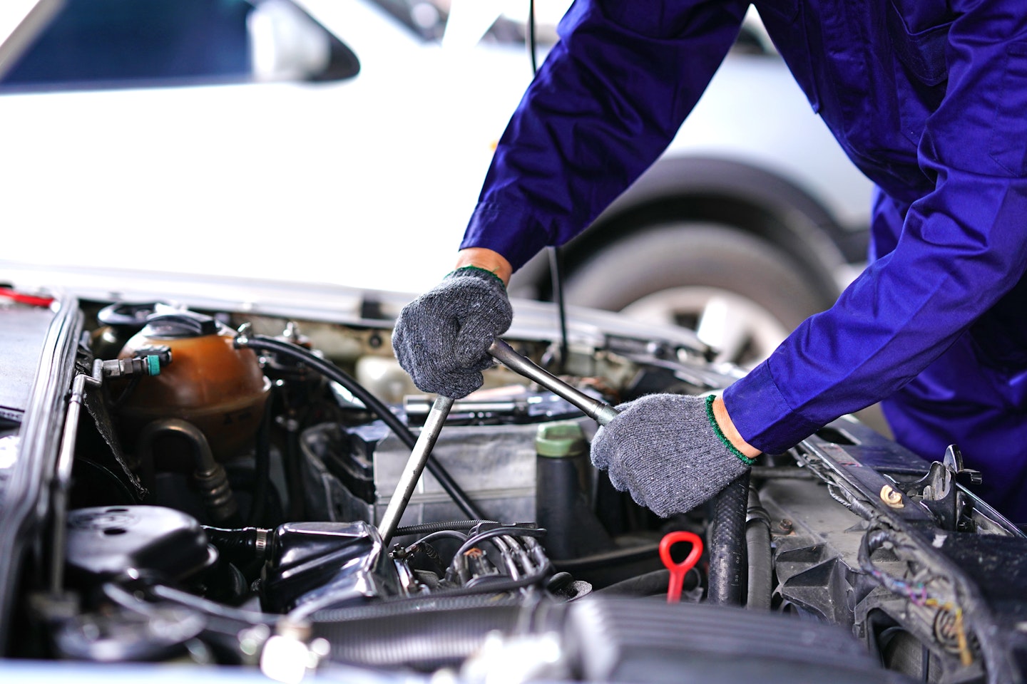 A mechanic using a wrench on a car 