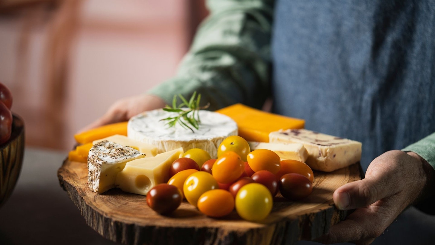 A colourful cheese-board held by someone.