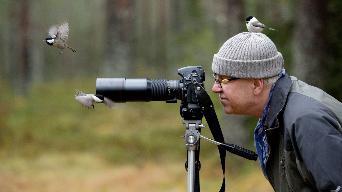 A man bird watching, with a bird in shot of his camera