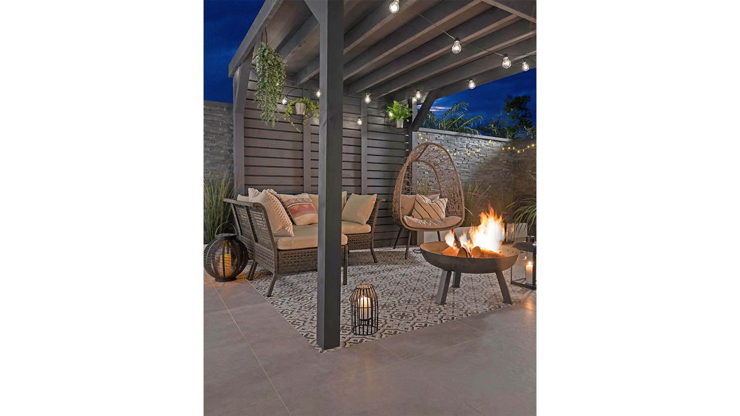 Patterned porcelain patio tiles at night with lanterns and fire pit