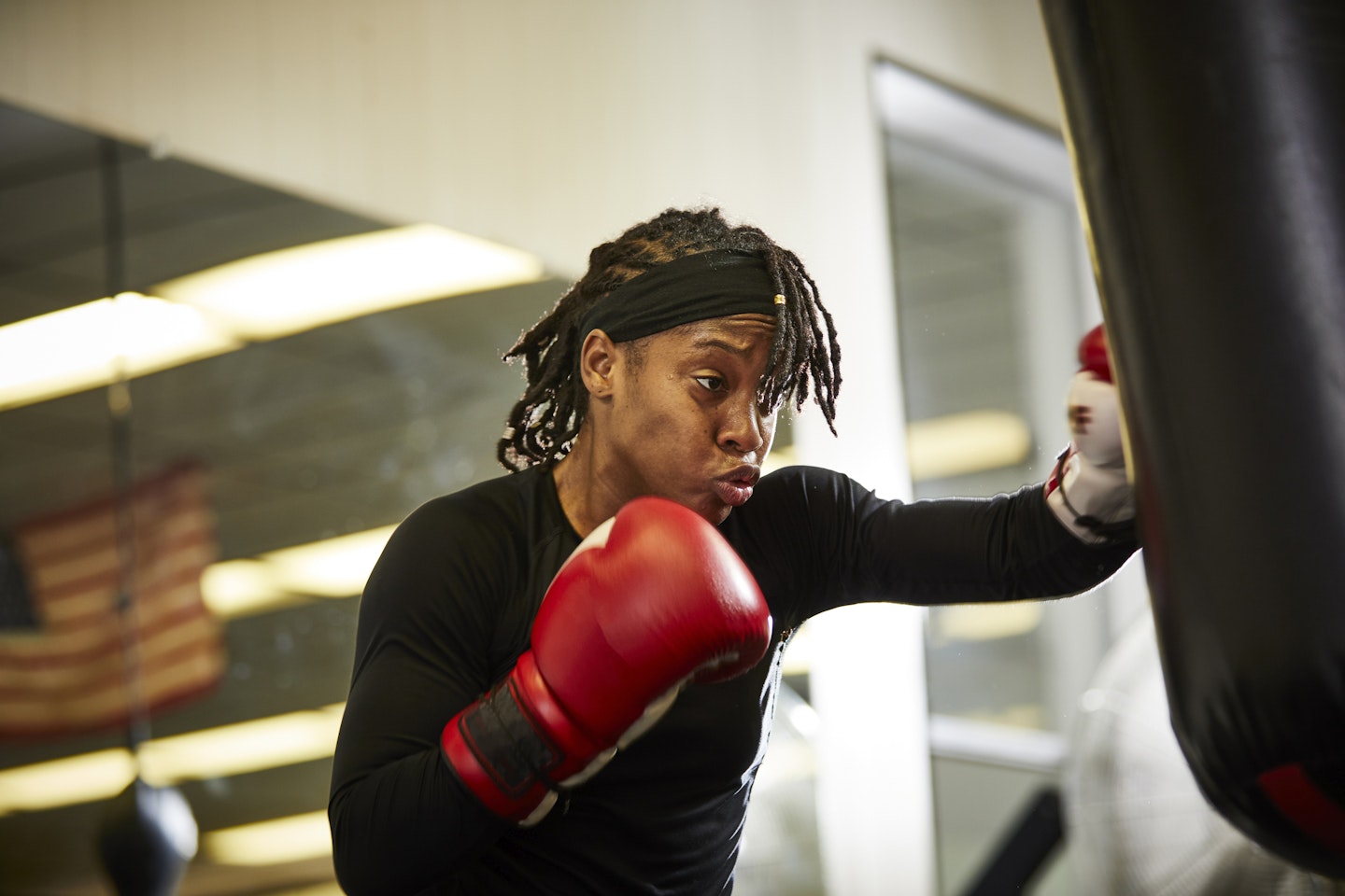 Woman wearing boxing gloves punching bag