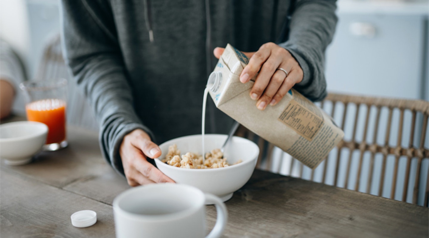 Pouring vegan milk onto a bowl of breakfast cereal