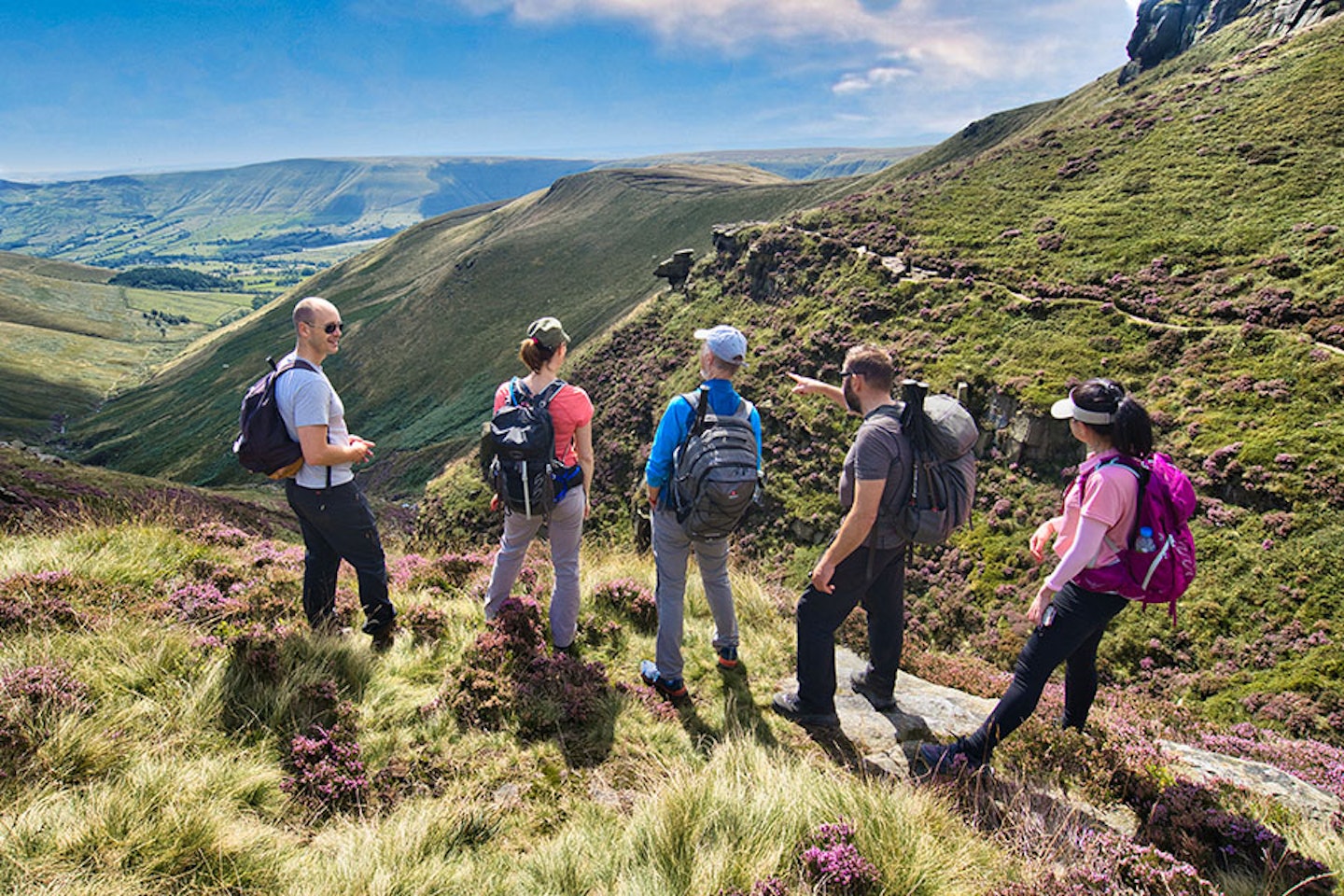 Walkers looking out over a view from Kinder Scout in the Peak District