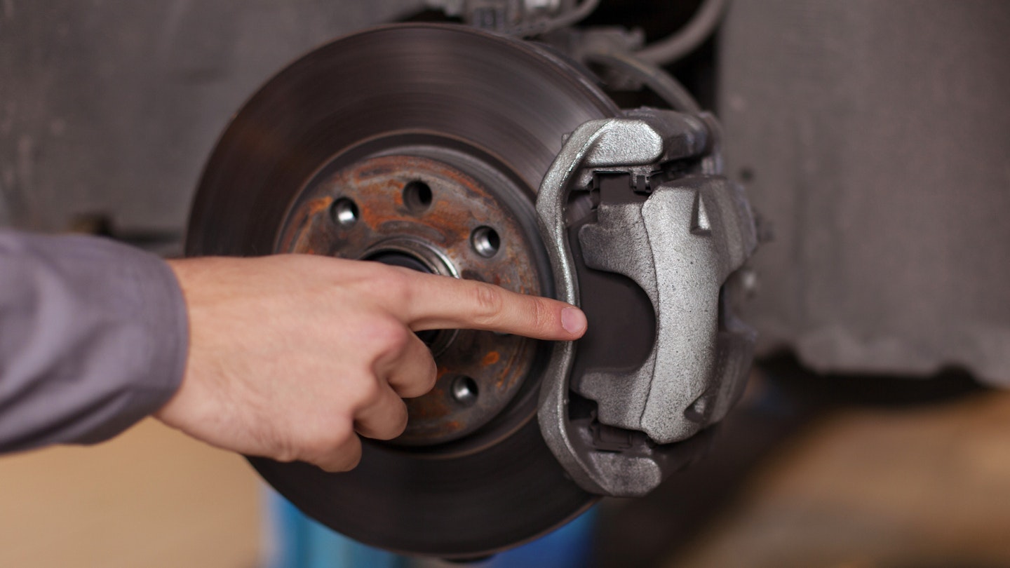 Finger pointing to a car brake pad