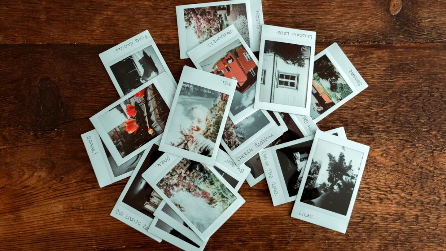 Instax refills: pile of Instax mini developed film on wooden table