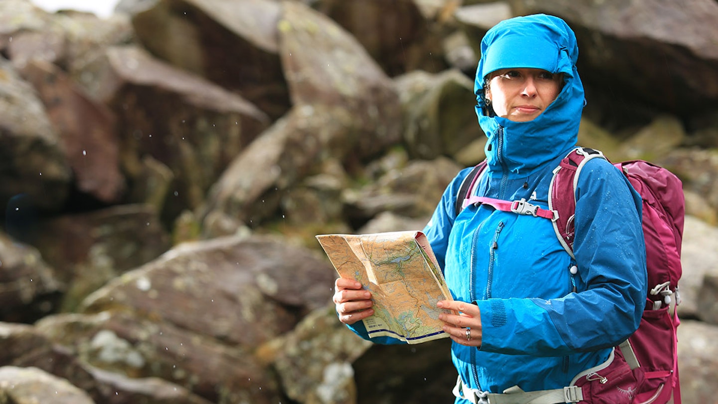Woman in hiking waterproof clothing with map