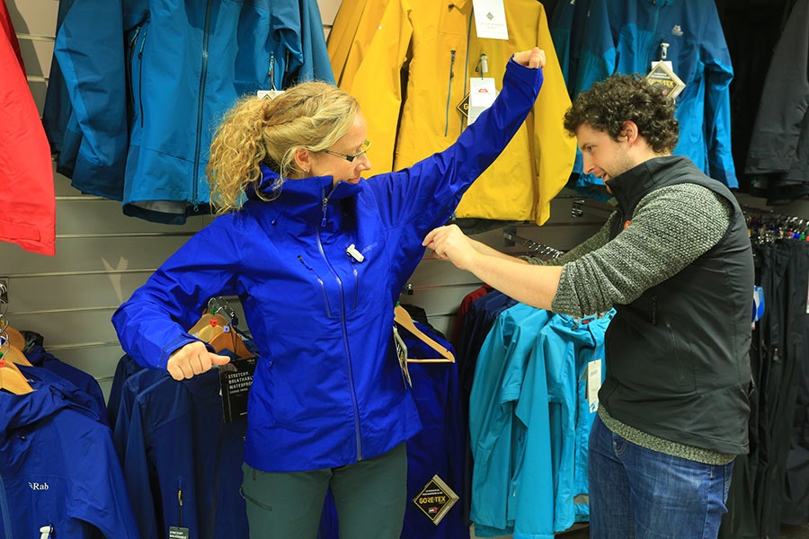 Woman trying waterproof jacket in gear shop
