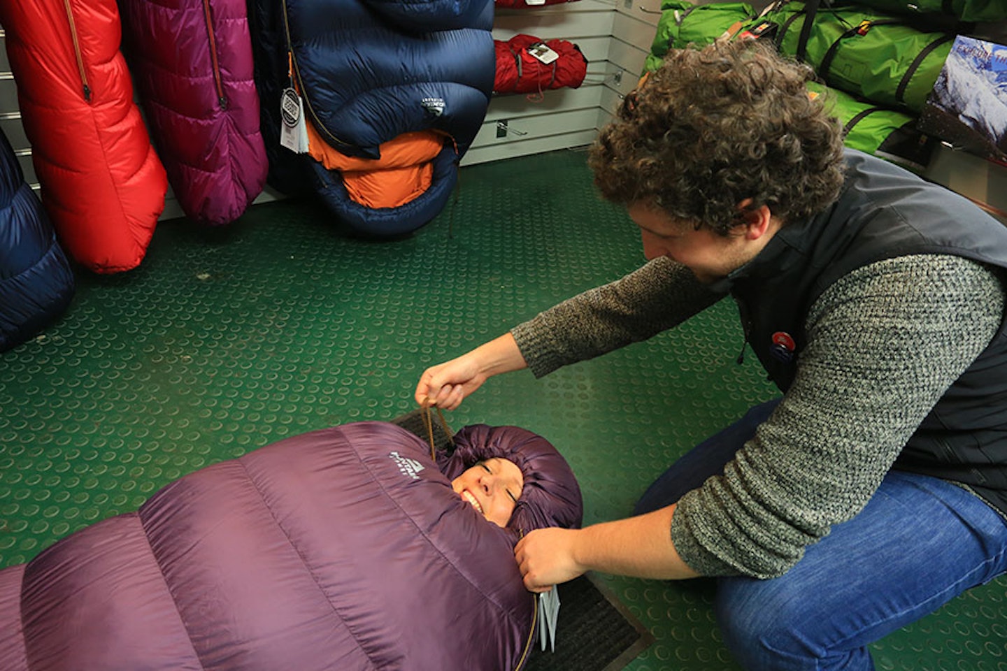 Woman in sleeping bag in a shop with assistant