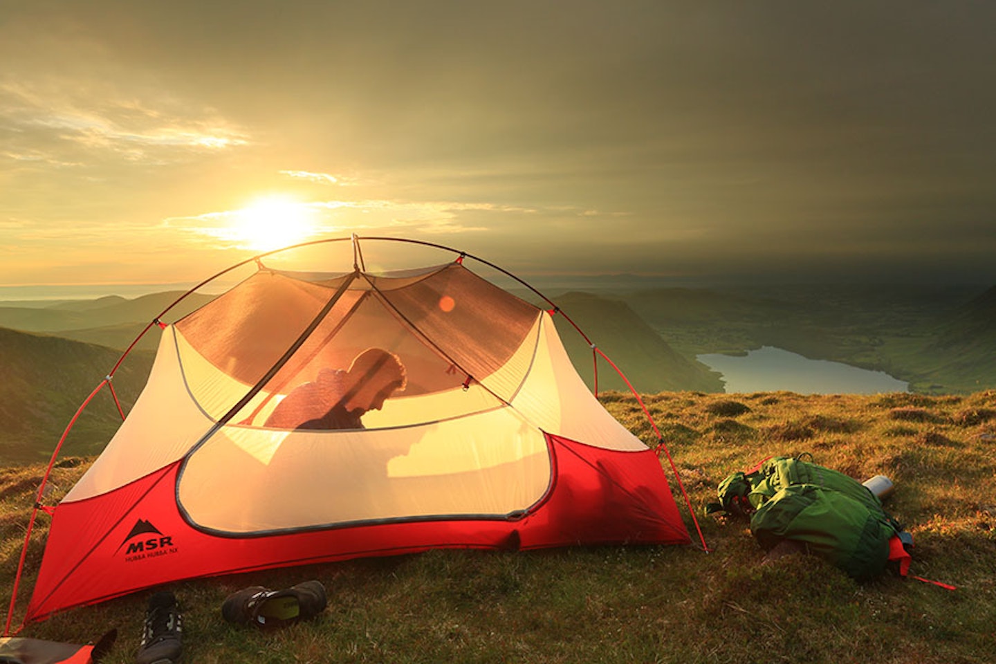 Sunset camping in a mesh tent with rucksack and mountain view