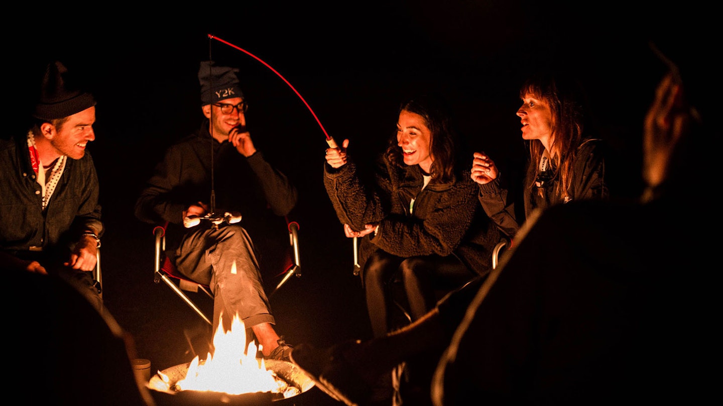 People around a camp fire laughing at night