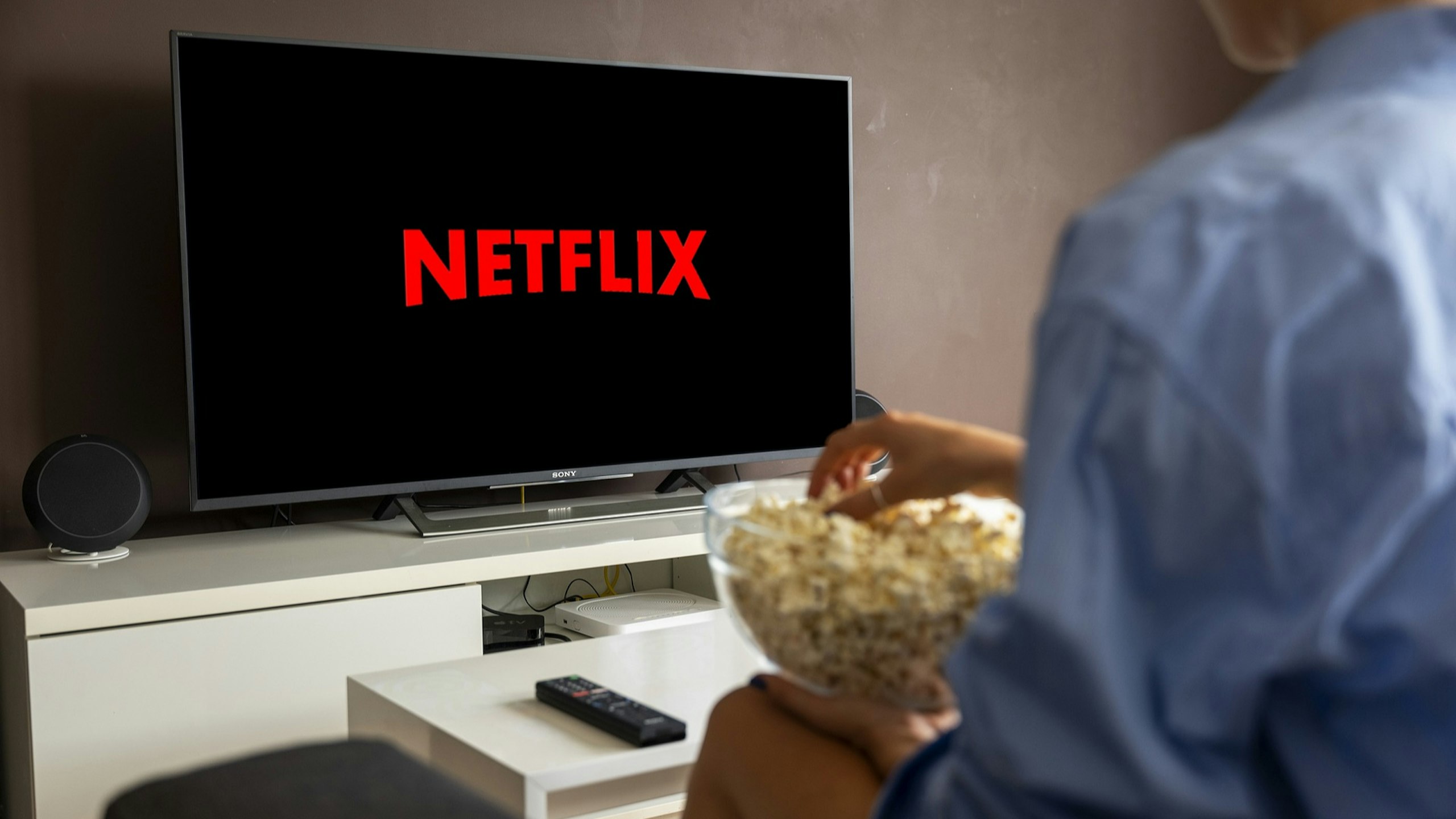 An image of a woman with popcorn watching TV