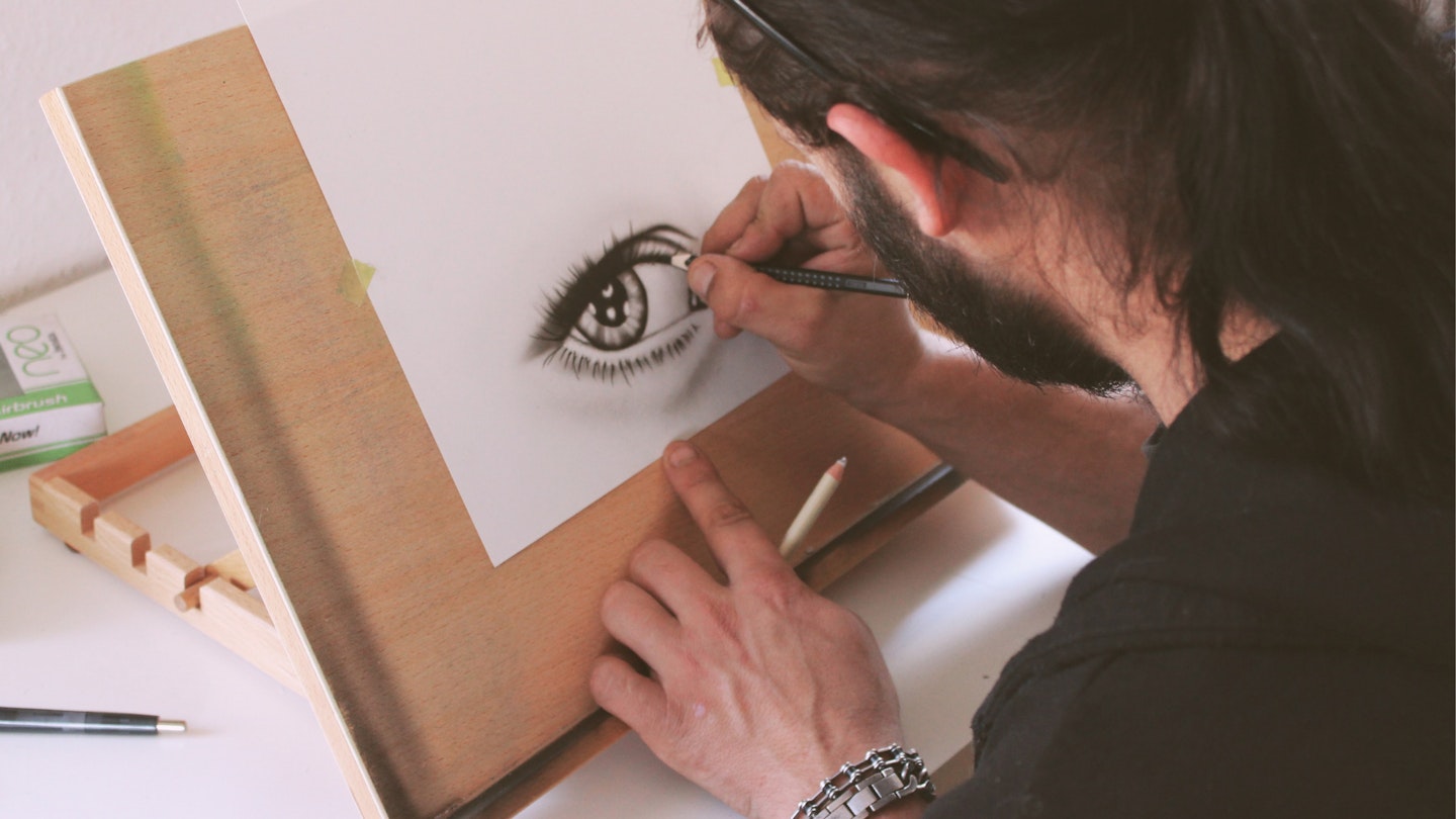 man drawing an eye with pencils