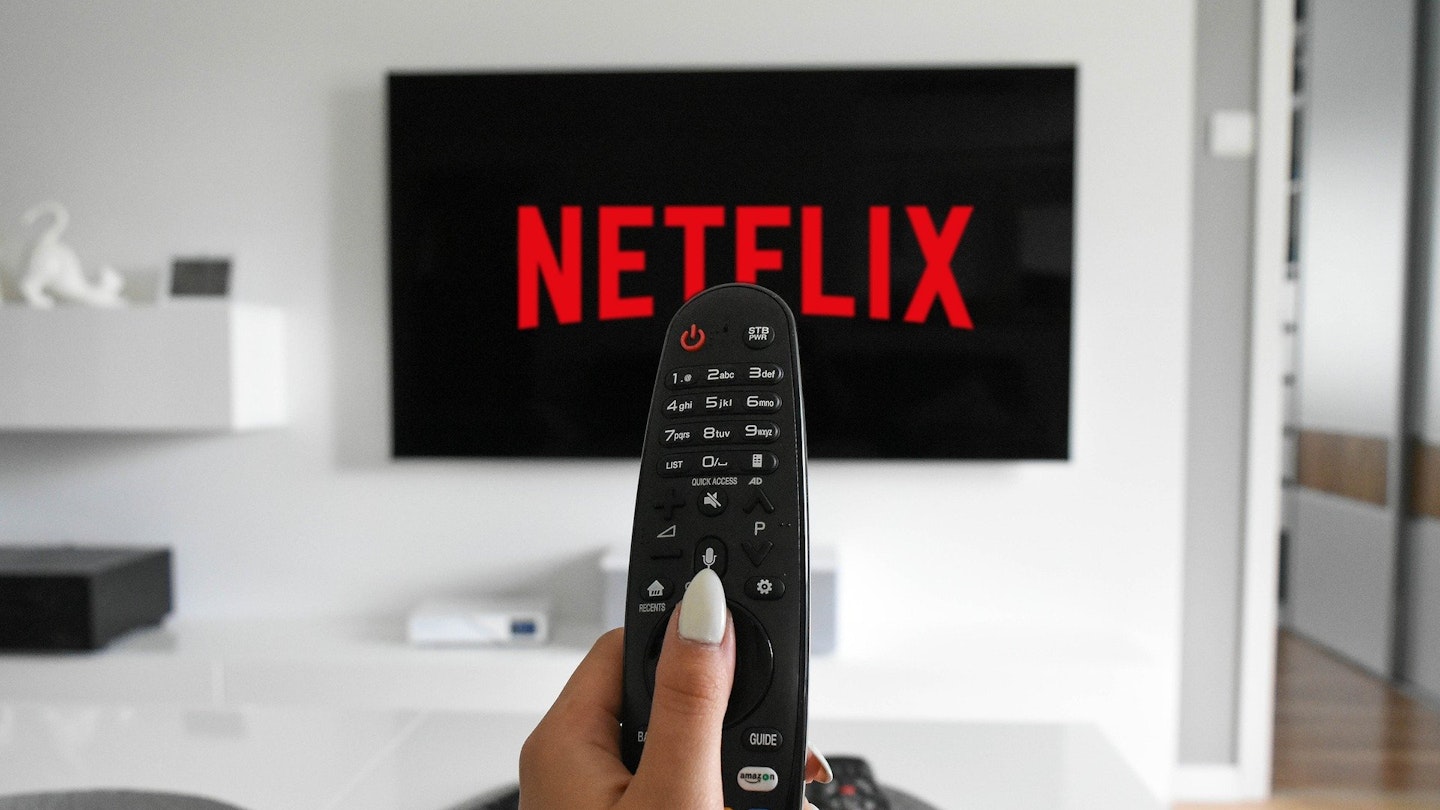 An image of someone watching Netflix, holding a remote control