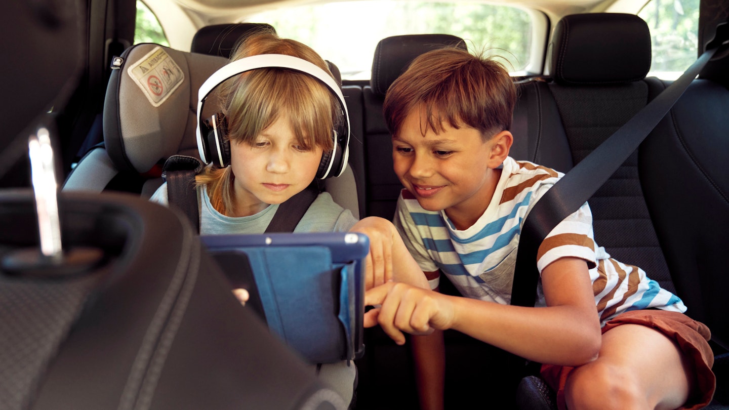 Children in car looking at smart tablet