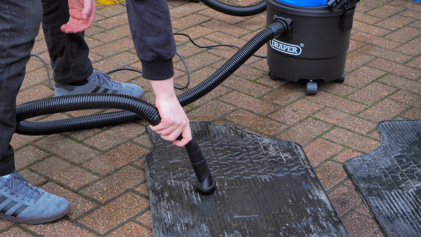Draper vacuum cleaning a wet car floor mat