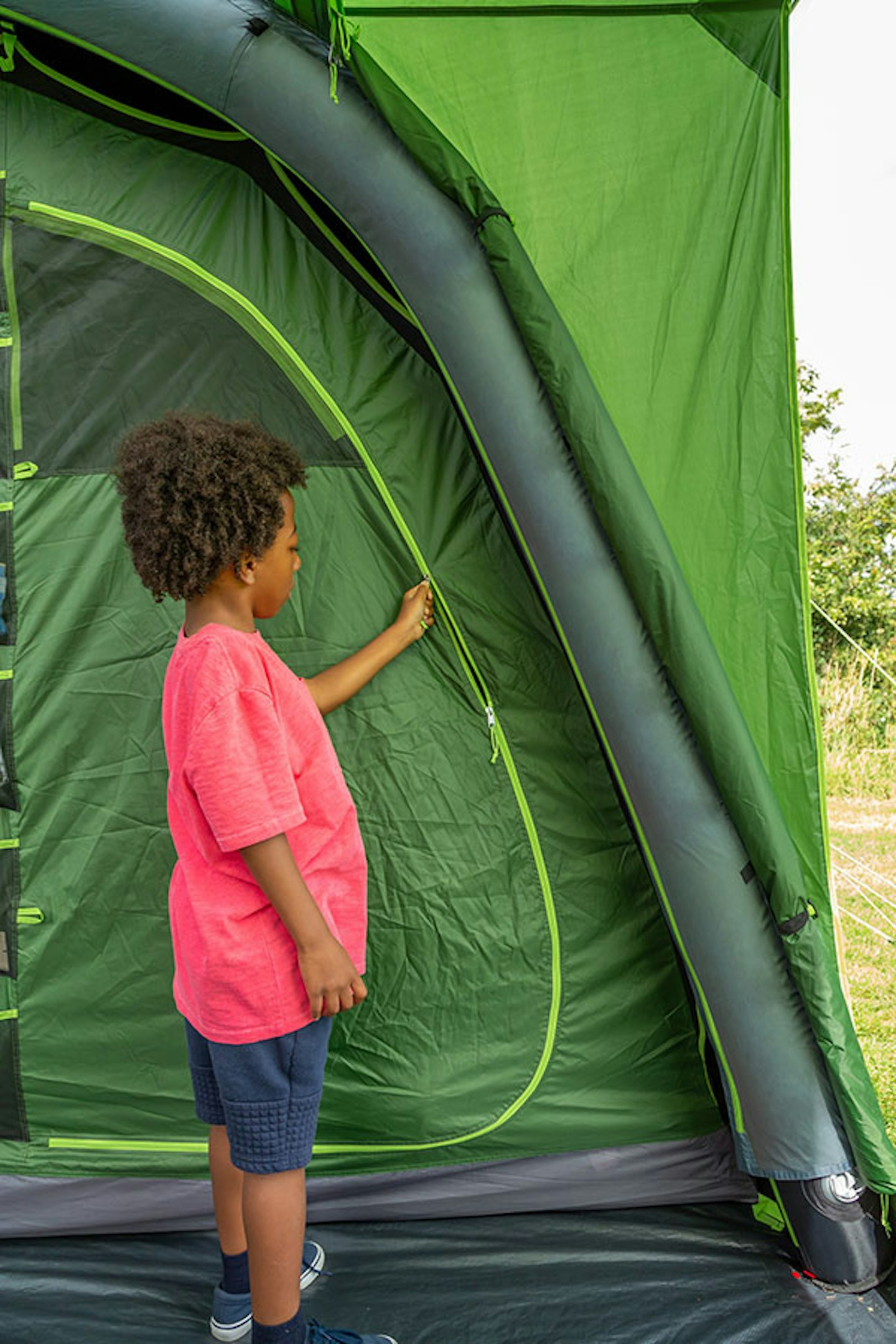 Child unzipping a green tent