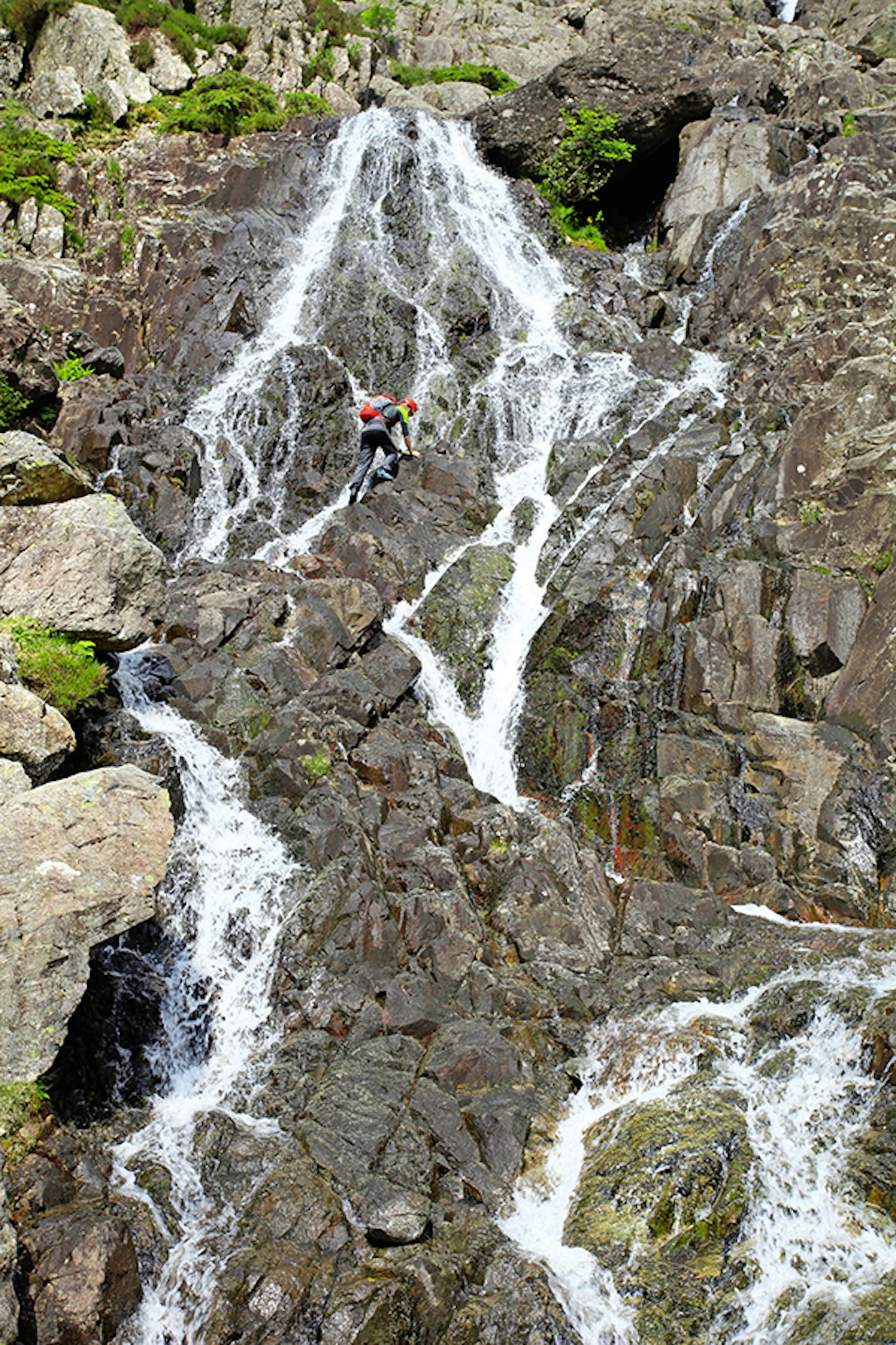 man in helmet climbing up a waterfall