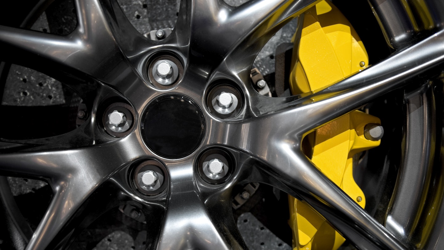 An alloy wheel with lug nuts and a yellow brake caliper