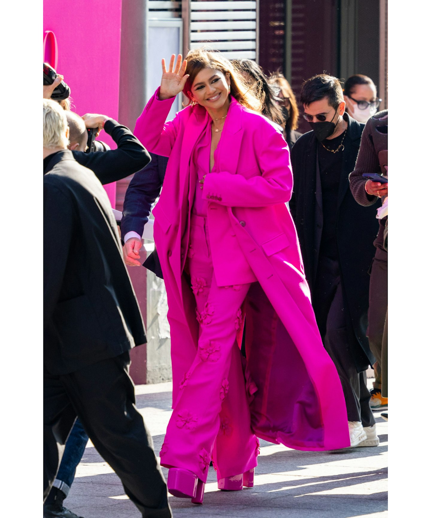 zendaya waving to fans as she wears the pink valentino suit 