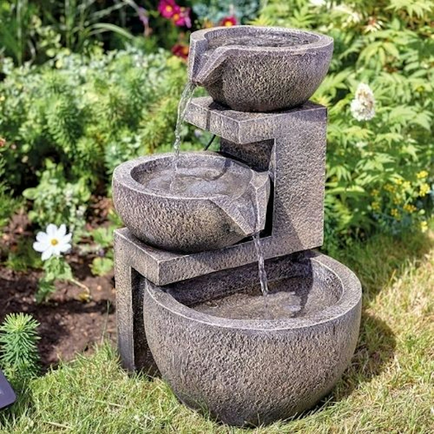 tiered water feature on grass in sunny garden