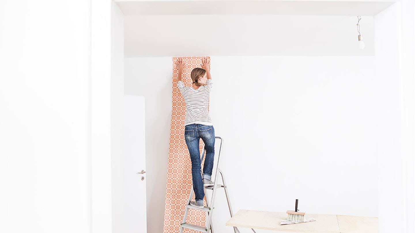 Woman hanging wallpaper